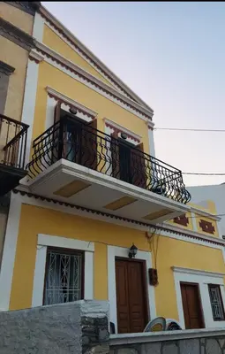 a yellow and white house with a balcony at Casa Kalliroi in Symi