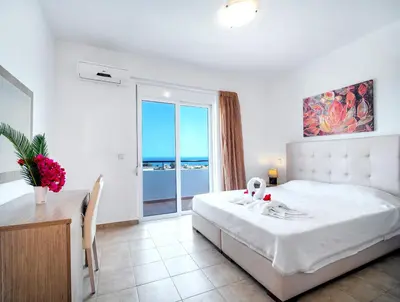 a white bedroom with a large bed and a window at Gennadi Gardens Apartments & Villas in Gennadi