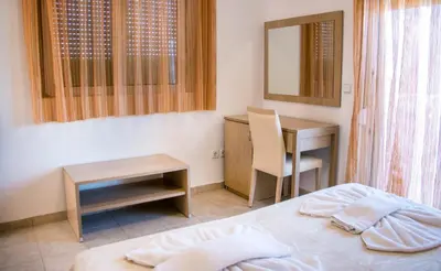 a bedroom with a bed and a table and a desk at Gennadi Gardens Apartments & Villas in Gennadi
