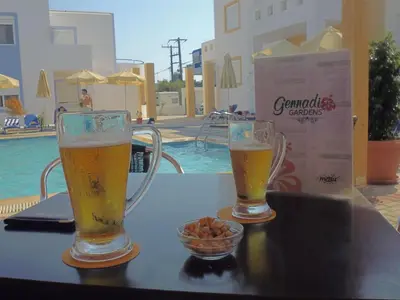 two glasses of beer on a table next to a pool at Gennadi Gardens Apartments & Villas in Gennadi