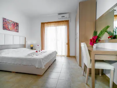 a bedroom with a bed and a table and a desk at Gennadi Gardens Apartments & Villas in Gennadi