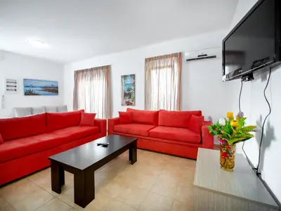 a living room with red couches and a tv at Gennadi Gardens Apartments & Villas in Gennadi