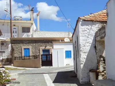 an alley with a white building with blue windows at Amaliahotel in Apolakkiá