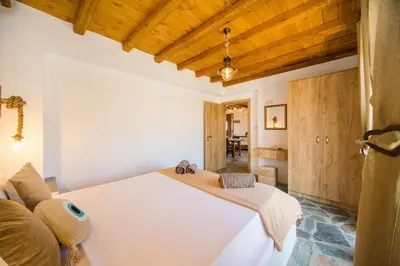 a bedroom with a large white bed and wooden ceilings at Pitropos Garden in Archangelos
