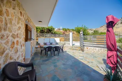 a patio with a table and chairs on a stone wall at Pitropos Garden in Archangelos