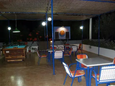 a patio with tables and chairs and a pool table at Vera Studios in Faliraki
