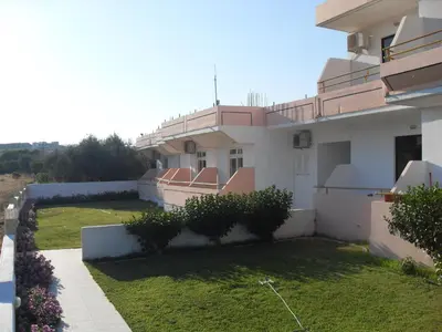 a white house with a yard with grass and flowers at Vera Studios in Faliraki