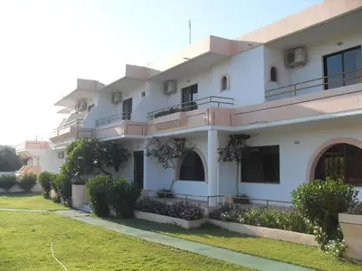 a large white building with balconies and a yard at Vera Studios in Faliraki