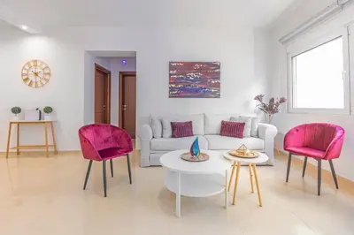 a living room with a white couch and pink chairs at Central Luxurious Apartments Close to the Sea in Rhodes Town