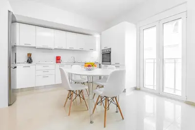 a white kitchen with a white table and chairs at Central Luxurious Apartments Close to the Sea in Rhodes Town