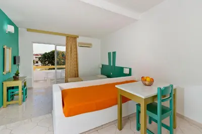 a bedroom with a bed and a table with a dining room at Trianta Hotel Apartments in Ialyssos