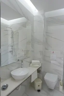 a white bathroom with a sink and a toilet at Trianta Hotel Apartments in Ialyssos