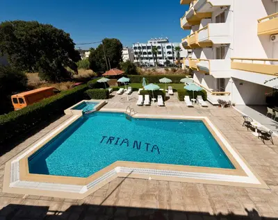 a swimming pool in front of a building at Trianta Hotel Apartments in Ialyssos