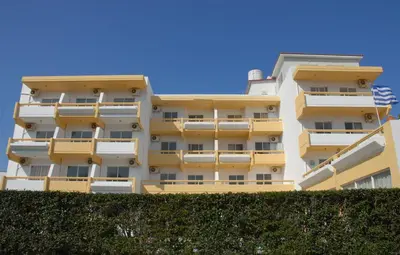 a yellow apartment building with a hedge in front of it at Trianta Hotel Apartments in Ialyssos