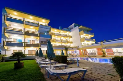 a hotel with chairs and umbrellas in front of a building at Trianta Hotel Apartments in Ialyssos