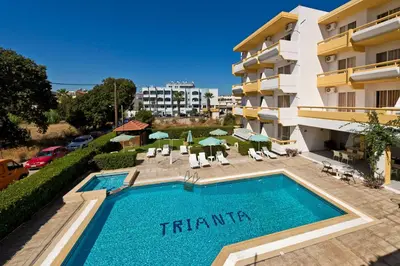 a swimming pool in front of a building at Trianta Hotel Apartments in Ialyssos