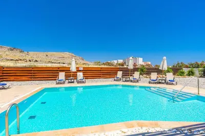 a swimming pool with chaise lounge chairs and a swimming pool at Villa Ophelia in Líndos