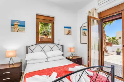 a bedroom with a bed and a sliding glass door at Villa Ioanna in Líndos