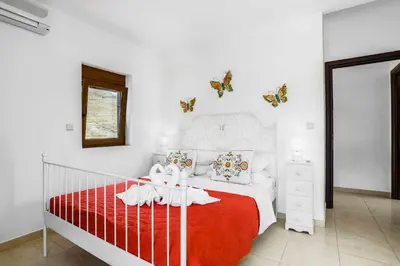 a bedroom with a red and white bed with butterflies on the wall at Villa Ioanna in Líndos