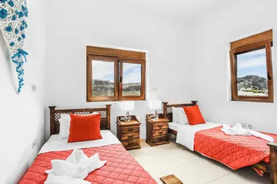 a bedroom with two beds and two windows at Villa Ioanna in Líndos