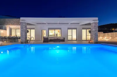 a large swimming pool in front of a house at night at Villa Hermes with pool & jacuzzi in Lindos in Líndos