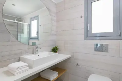 a white bathroom with a sink and a mirror at Villa Hermes with pool & jacuzzi in Lindos in Líndos