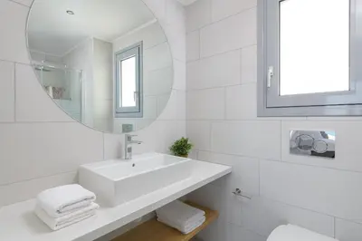 a white bathroom with a sink and a mirror at Villa Hermes with pool & jacuzzi in Lindos in Líndos