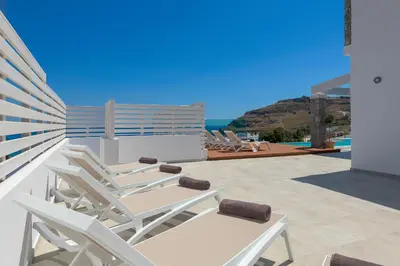 a group of lounge chairs on the roof of a house at Villa Hermes with pool & jacuzzi in Lindos in Líndos