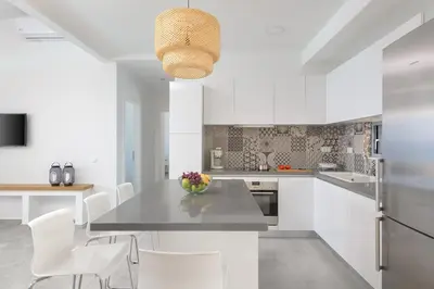 a white kitchen with a table and white chairs at Villa Hermes with pool & jacuzzi in Lindos in Líndos