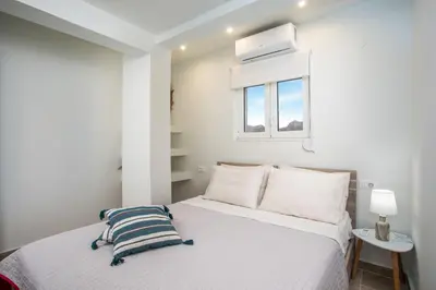 a white bedroom with a bed and a window at Stegna Paradise View in Archangelos