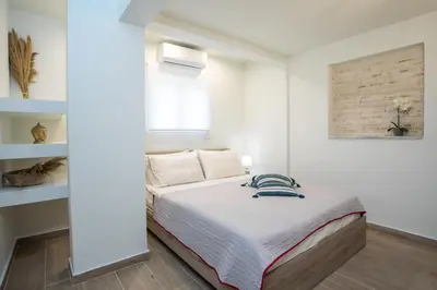 a white bedroom with a bed and a window at Stegna Paradise View in Archangelos