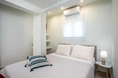 a white bedroom with a bed and a window at Stegna Paradise View in Archangelos