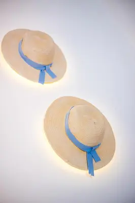 a straw hat with a blue ribbon on a white background at Papenas Cozy Home in Faliraki