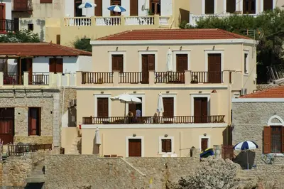 a white building with a balcony with an umbrella at Villa Amalia in Halki
