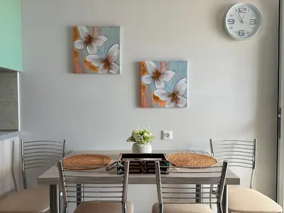 a dining room table with four chairs and a clock at M&N Apartments in Archangelos