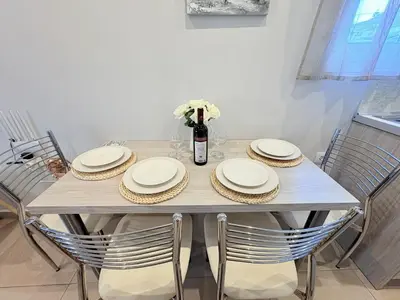 a table with chairs and plates and a vase of flowers at M&N Apartments in Archangelos