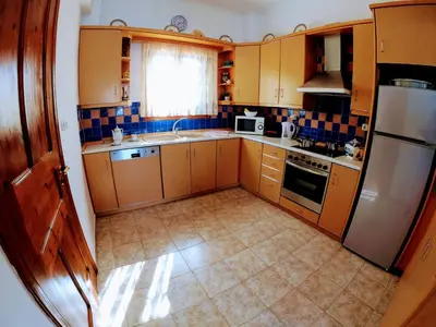 a small kitchen with wooden cabinets and a refrigerator at Korali in Symi