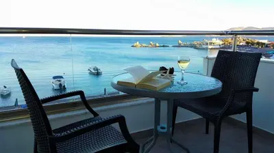 a table with a book and a glass of wine on a balcony at Haraki Blue Pearl in Haraki