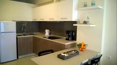 a kitchen with a white refrigerator and a table with fruits on it at Haraki Blue Pearl in Haraki