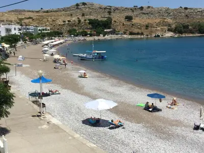 a group of people sitting on a beach with umbrellas at Haraki Blue Pearl in Haraki