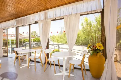 a patio with tables and chairs and windows at Marieta-Giannis in Faliraki