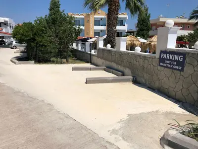 a retaining wall with a parking sign next to a sidewalk at Marieta-Giannis in Faliraki