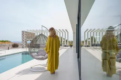 a woman in a yellow dress is looking into a building at amara luxury villas in Lachania