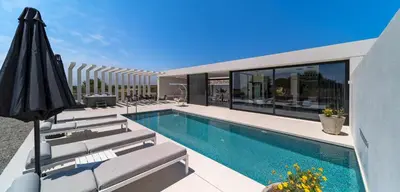 an outdoor swimming pool with chairs and an umbrella at amara luxury villas in Lachania