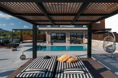 a house with a pool and a patio with a bench at amara luxury villas in Lachania