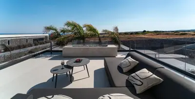 a patio with a table and chairs on a balcony at amara luxury villas in Lachania