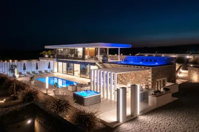 a building with a swimming pool at night at amara luxury villas in Lachania