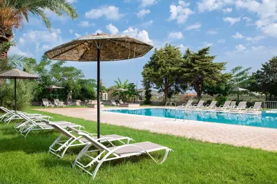 a group of chairs and an umbrella next to a pool at Rose Hotel Faliraki in Faliraki
