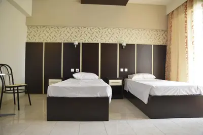 a bedroom with two beds and a chair at Rose Hotel Faliraki in Faliraki