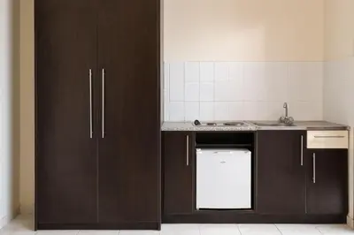 a kitchen with brown cabinets and a sink and a dishwasher at Rose Hotel Faliraki in Faliraki